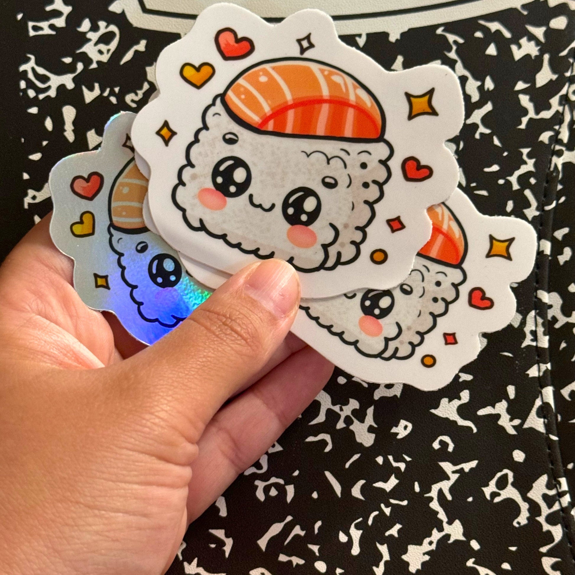 a hand holding a sticker with a sushi character on it