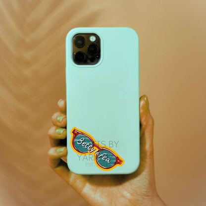 a person holding a cell phone with a sticker on it