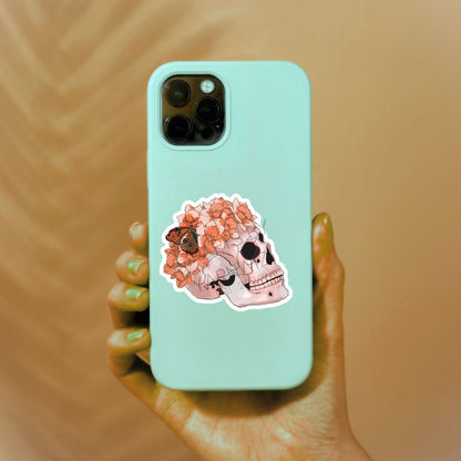 a person holding a phone case with a skull sticker on it