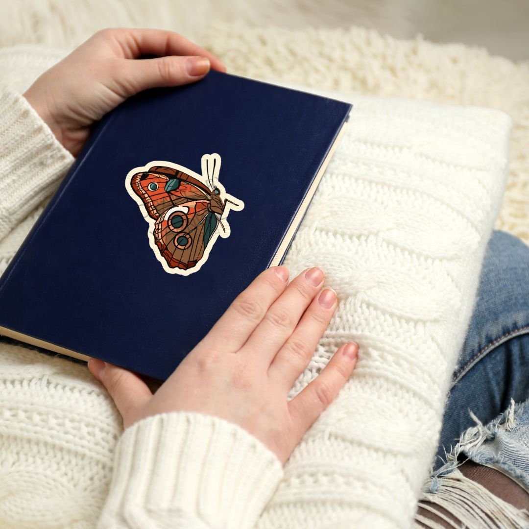 a person holding a book with a butterfly sticker on it